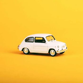 A white toy car on a yellow background